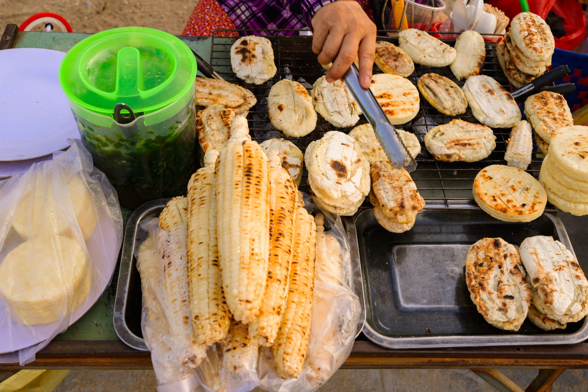 Close-up of Vietnamese street food with grilled corn and rice cakes at a local market.