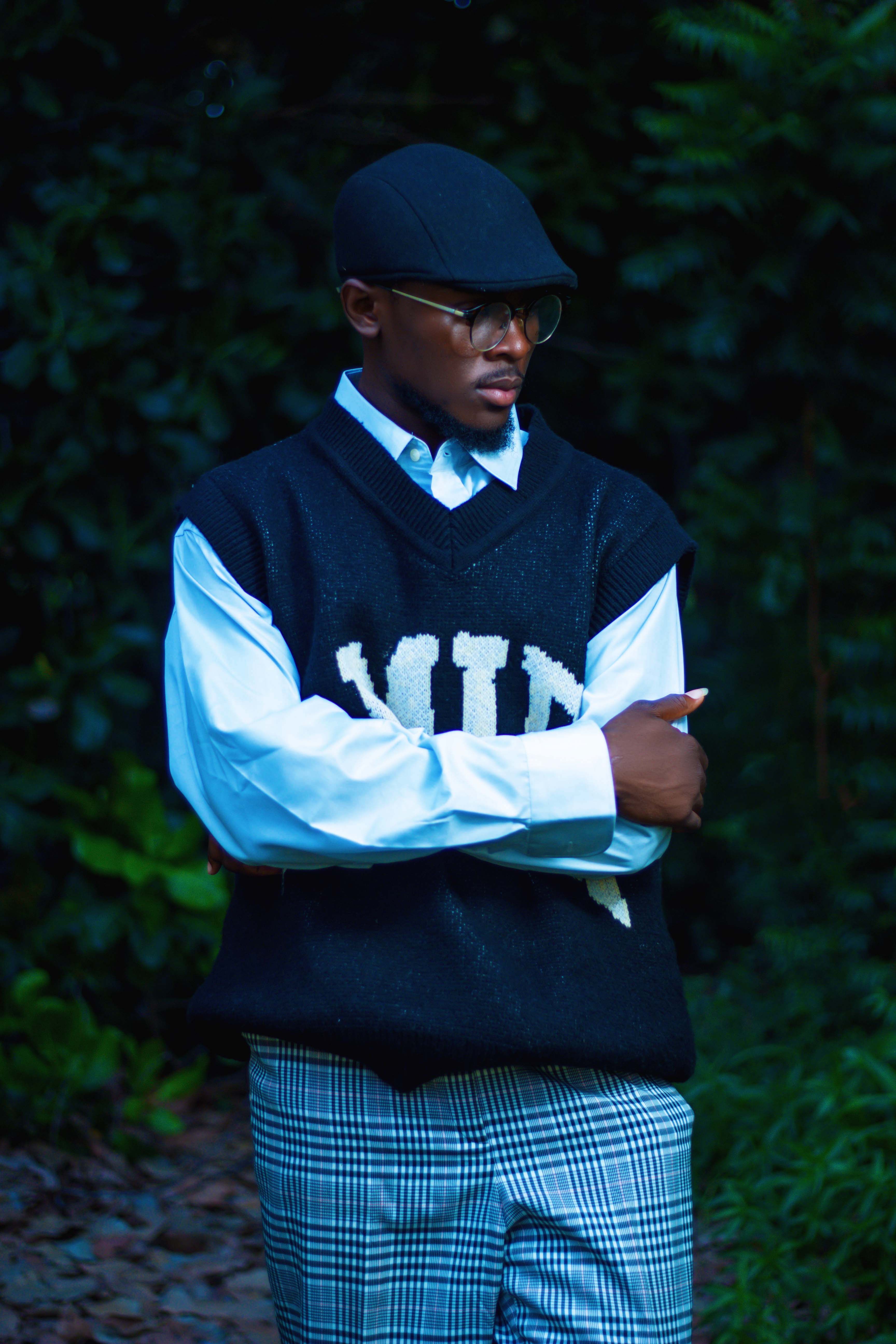 Fashionable man in vintage outfit standing outdoors with crossed arms.