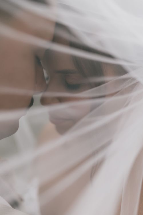 Free Intimate close-up of bride and groom under veil, embracing tenderly. Perfect for wedding themes. Stock Photo