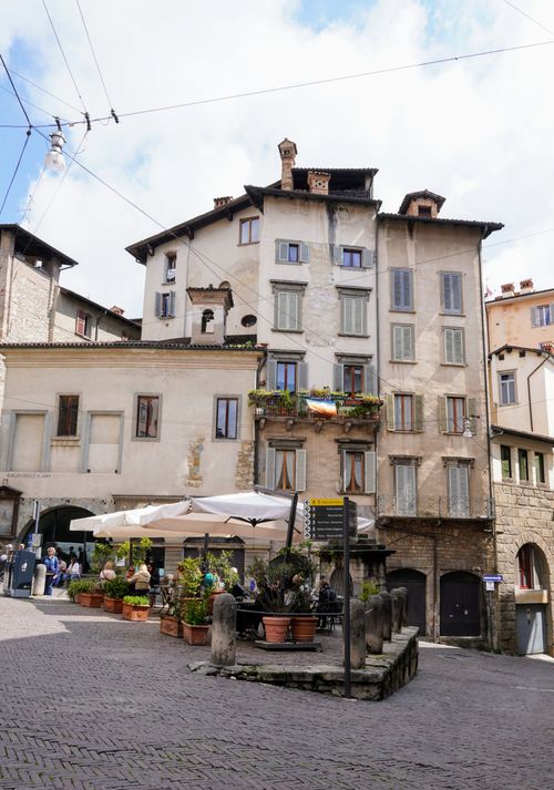 Free Quaint Italian street with historic architecture and outdoor cafe in a sunny setting. Stock Photo