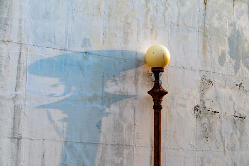 Free A vintage street lamp casts an artistic shadow against a textured, weathered wall, conveying a sense of nostalgia. Stock Photo