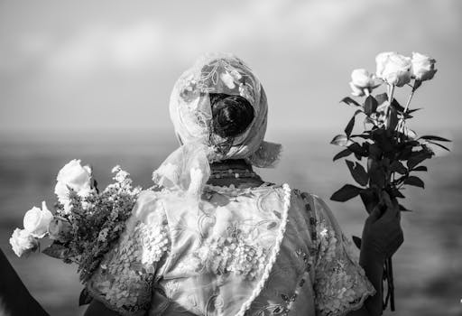 海边，一个穿着黑白相间衣服的女人拿着玫瑰的背影