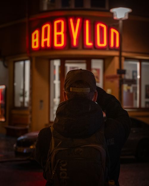 Free A person capturing the illuminated Babylon cinema sign in Berlin at night. Stock Photo