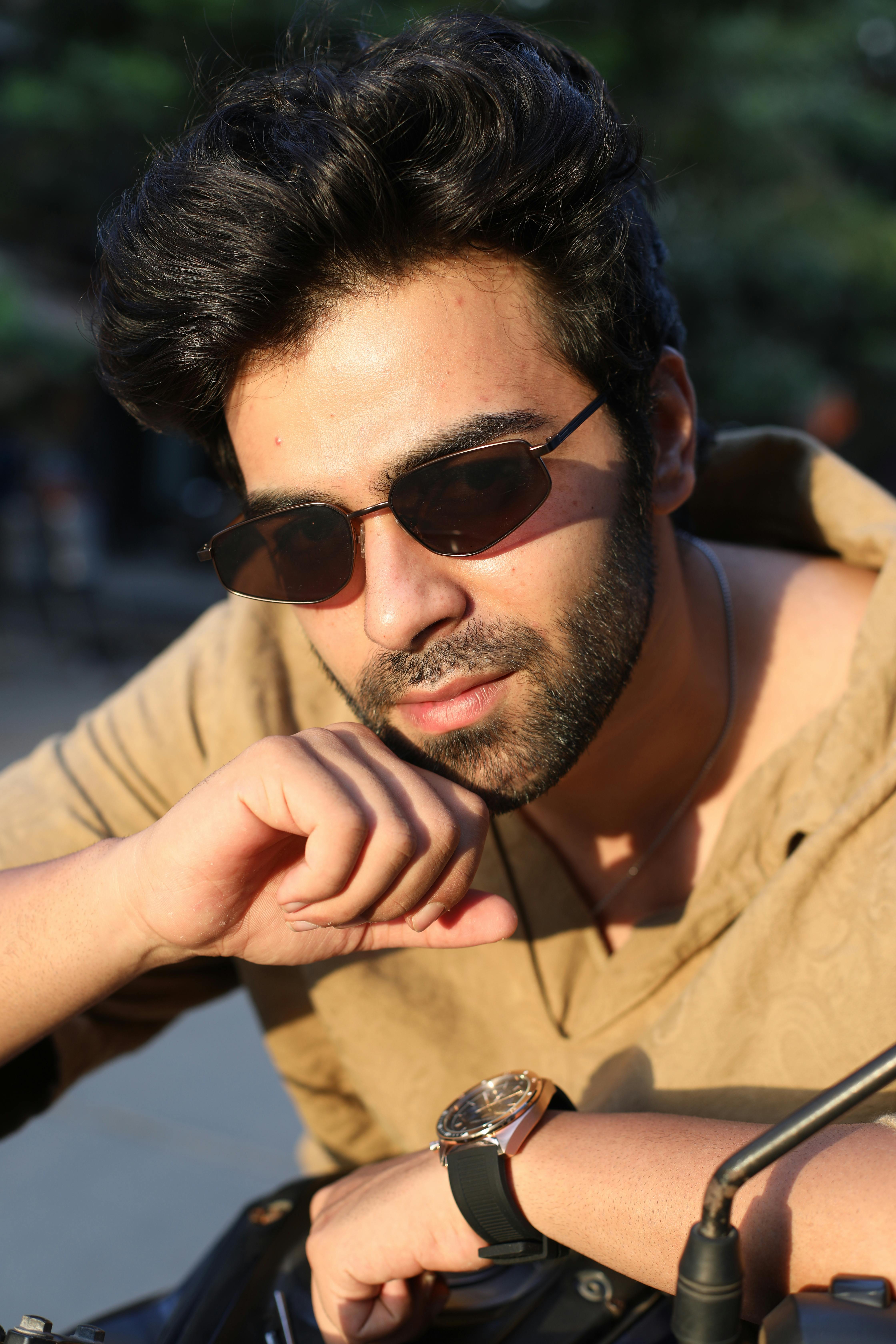 Portrait of a fashionable man wearing sunglasses, captured in warm daylight.
