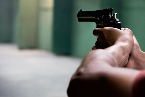 Person Holding Black Revolver in Bokeh Photography