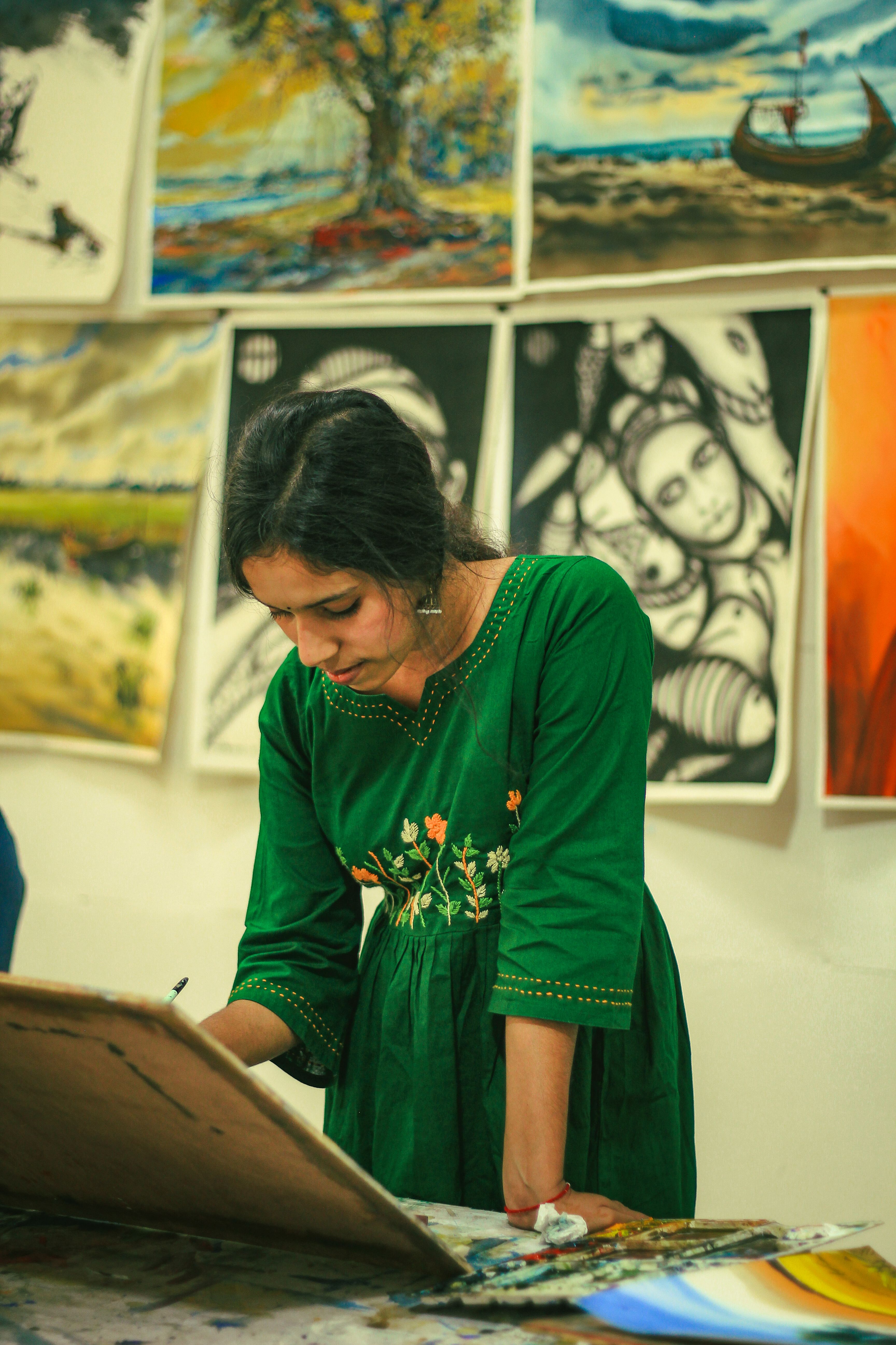 Female artist focused on painting during an art exhibition at Dhaka University.