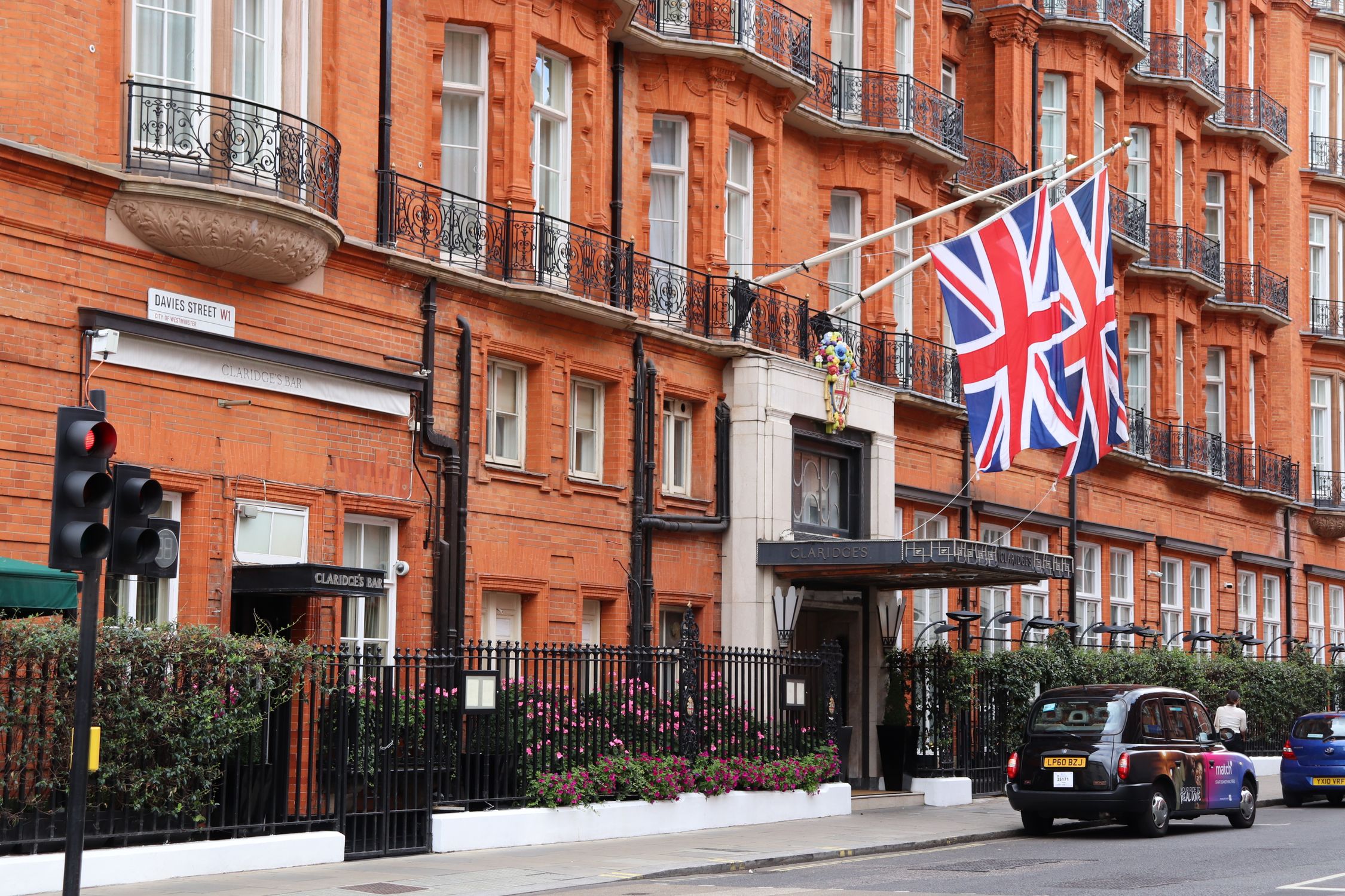Exterior of classic London hotel on a busy street with Union Jack flags displayed