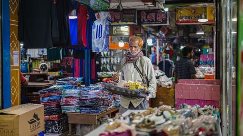 Free An elderly vendor selling goods in a crowded market in Dhaka, Bangladesh. Stock Photo