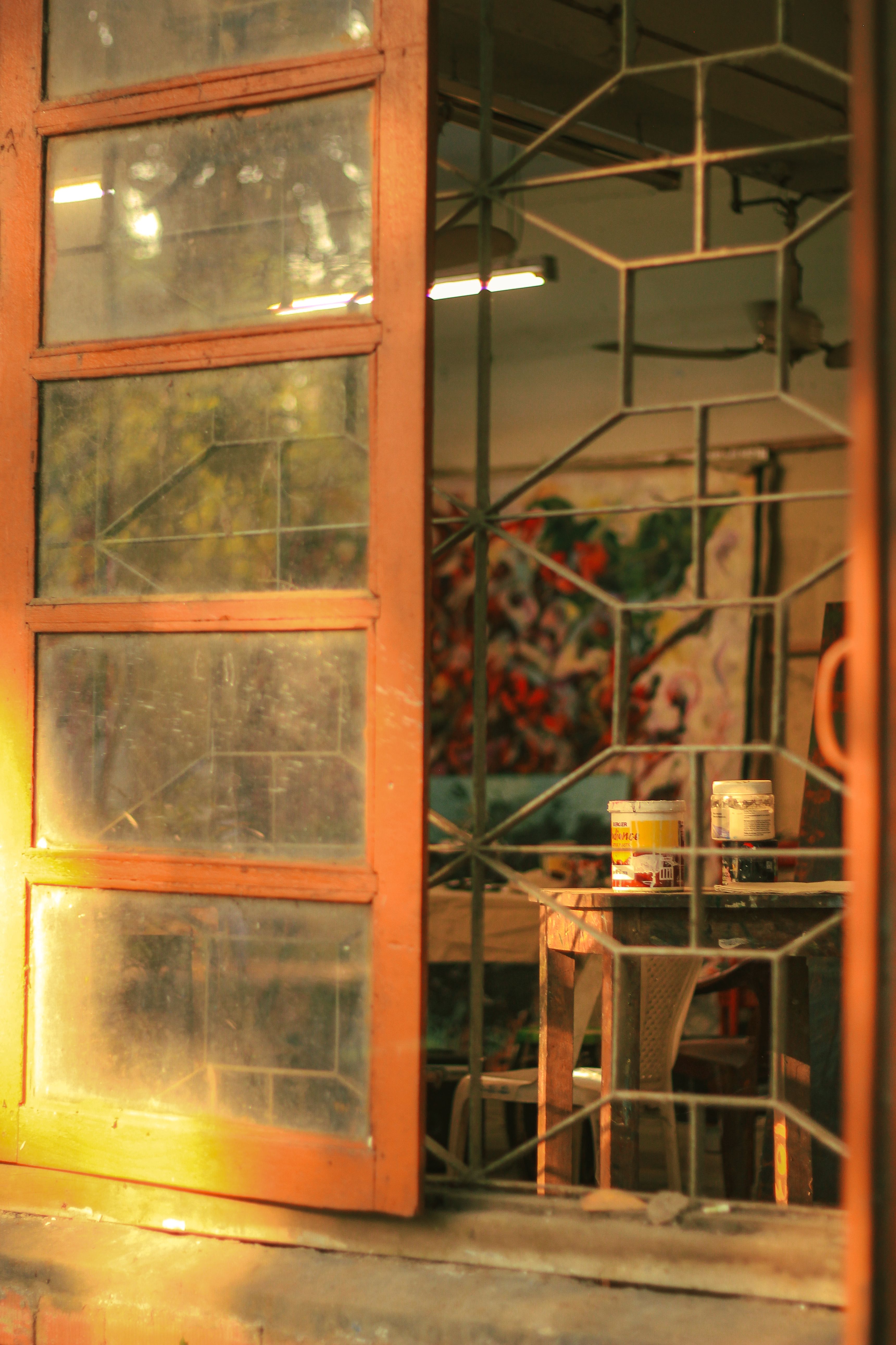 Sun-drenched studio window with art supplies inside, capturing creative essence in Dhaka.