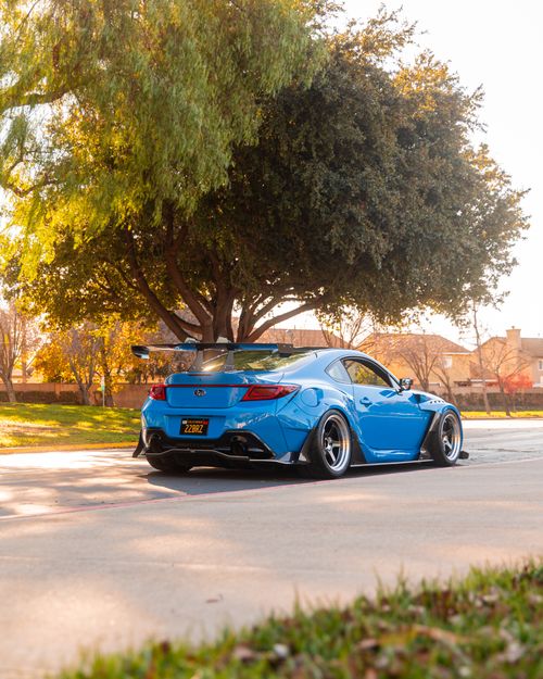 Free Vibrant blue sports car parked under a large tree in a sunny Tracy, CA park. Stock Photo