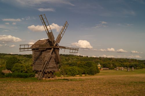 Free A rustic wooden windmill in the countryside of Pyrohiv, Kyiv, under a blue sky. Stock Photo