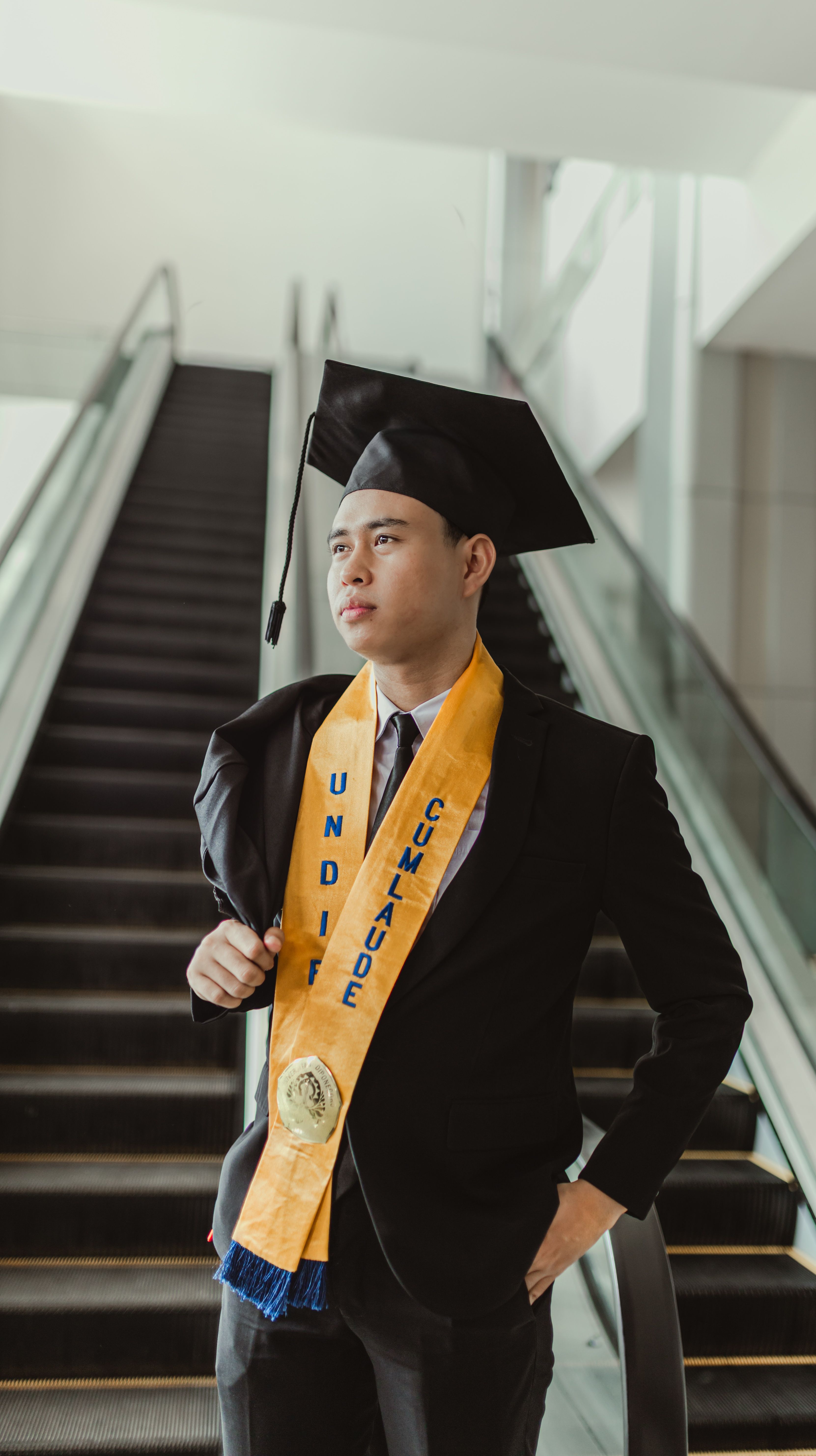 Young graduate posing proudly indoors with sash and cap in Kota Semarang, Indonesia.