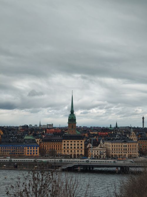 Free View of Stockholm's historic Old Town with overcast sky, iconic spires, and waterfront. Stock Photo