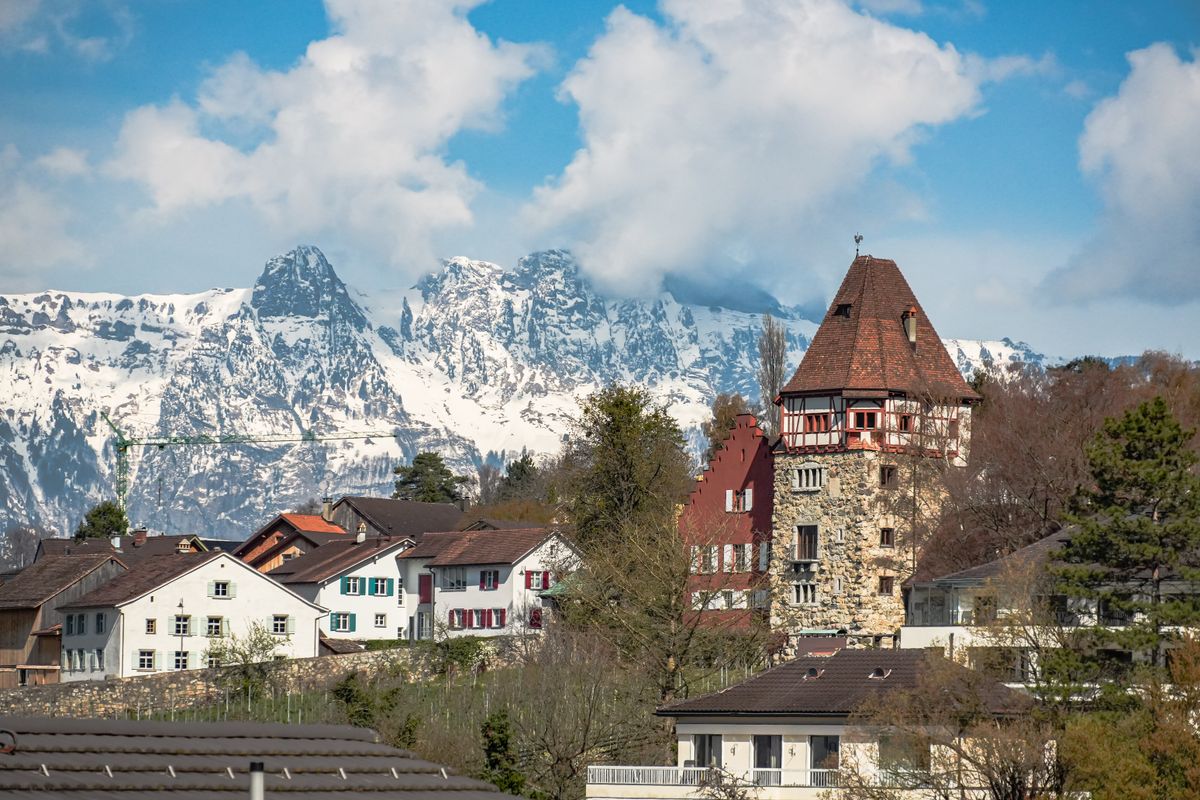 Case tradiționale din Balzers, cu turn medieval și Alpii înzăpeziți în fundal