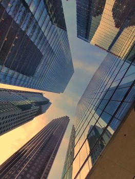 Looking up at Toronto's skyscrapers reflecting a sunset sky, showcasing modern architecture.