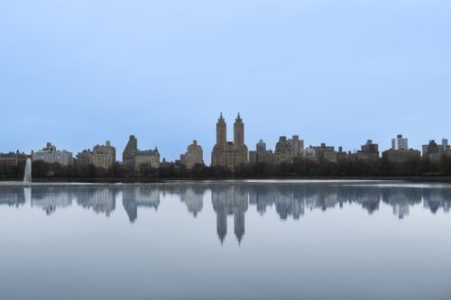 Free A serene view of New York City's skyline reflecting on calm water, showing architectural beauty. Stock Photo