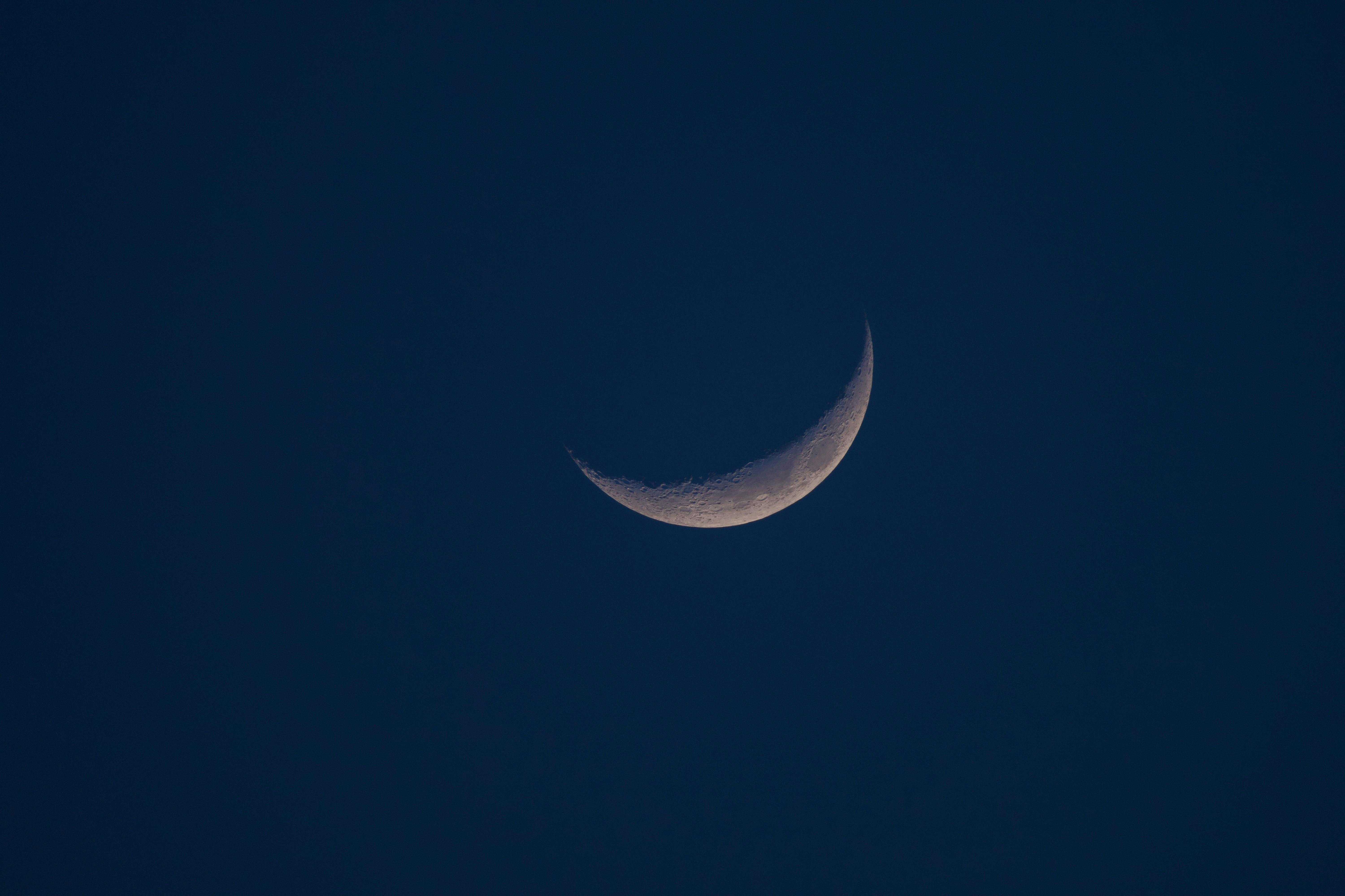 A close-up of a crescent moon against a dark night sky, highlighting lunar details.