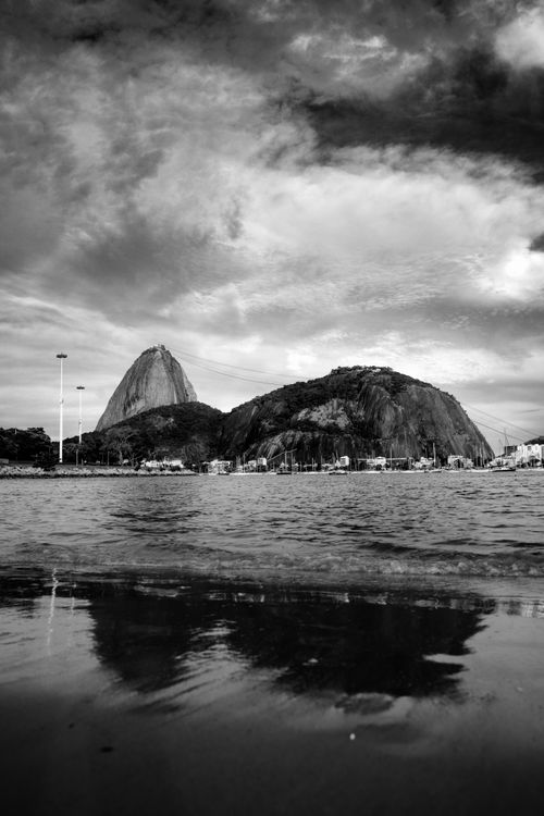 Free Dramatic black and white photograph of Sugarloaf Mountain in Rio de Janeiro, captured at the water's edge. Stock Photo