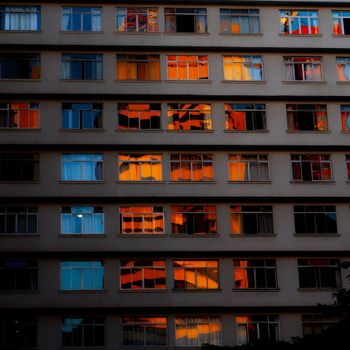 Stunning reflections of vibrant orange and blue hues in a building's windows in São Paulo at sunset.