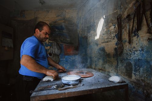 Free An artisan baker making traditional bread in a rustic kitchen with clay oven. Stock Photo