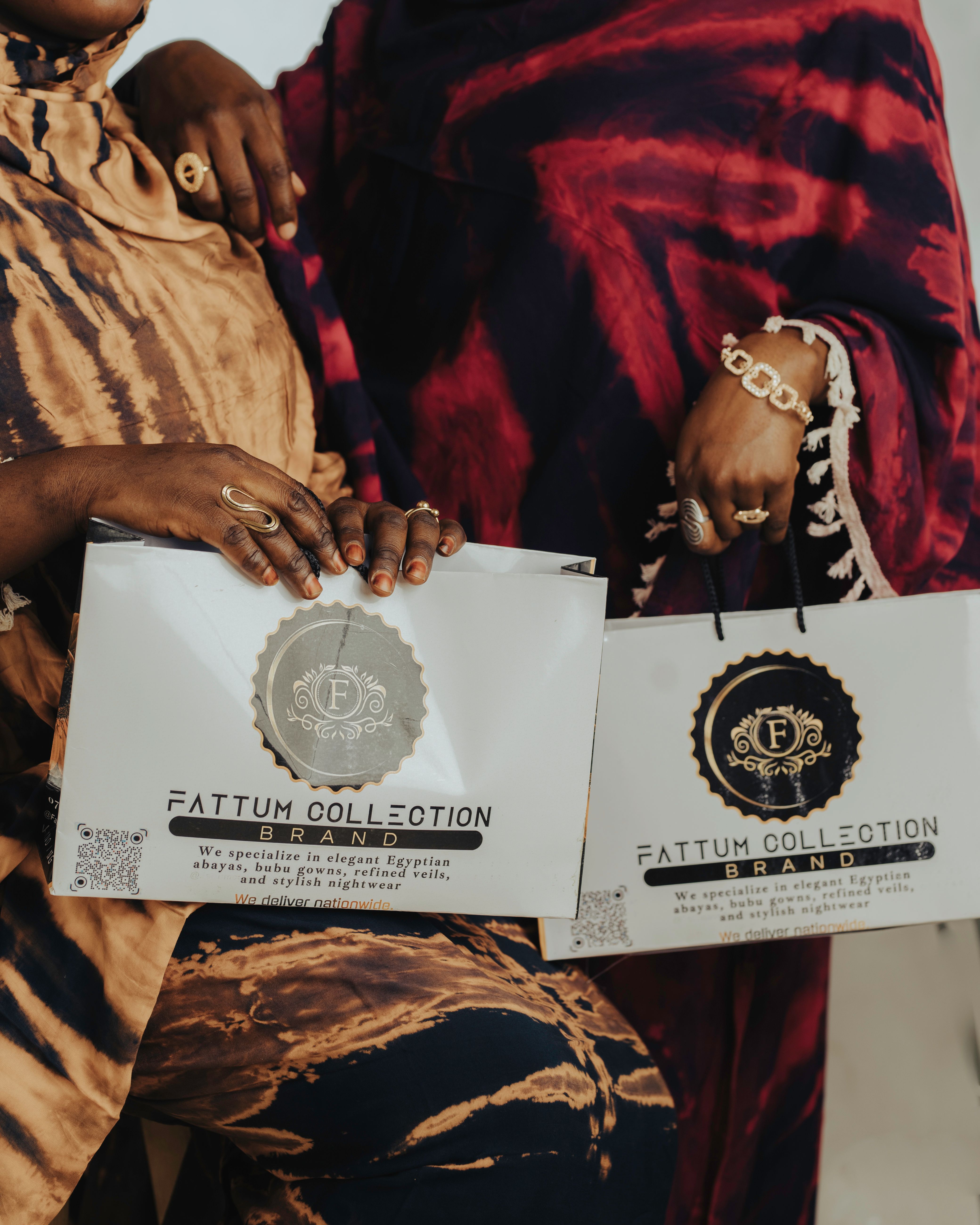 Two individuals showcasing branded shopping bags from Fattum Collection with stylish attire and accessories.