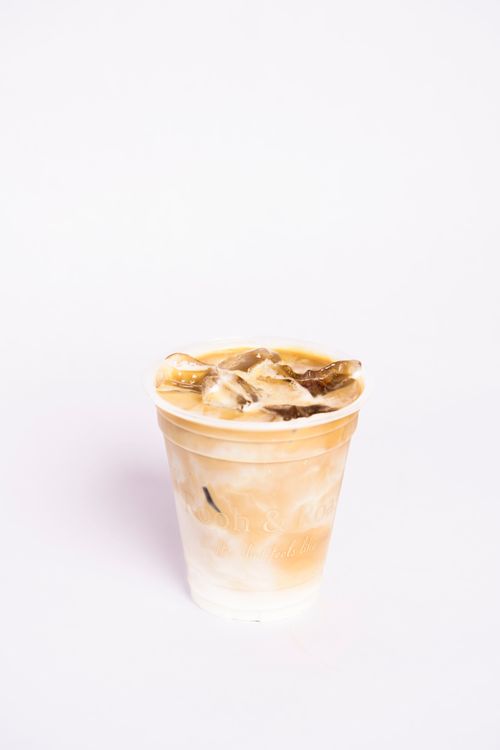 Free Aesthetic iced coffee cup filled with ice and creamy coffee on a clean white background. Stock Photo