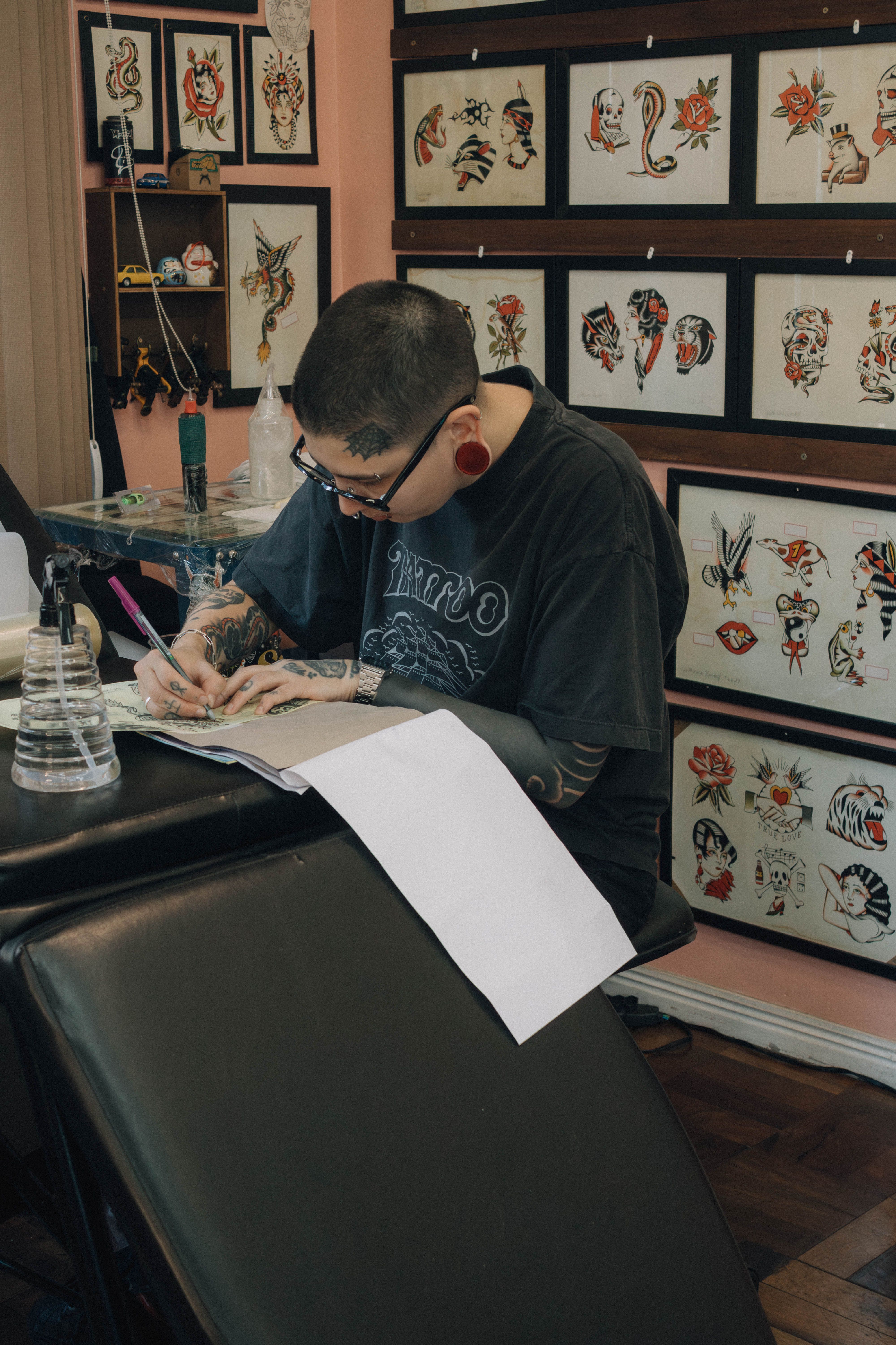 Tattooed artist sketching a custom design in a notebook