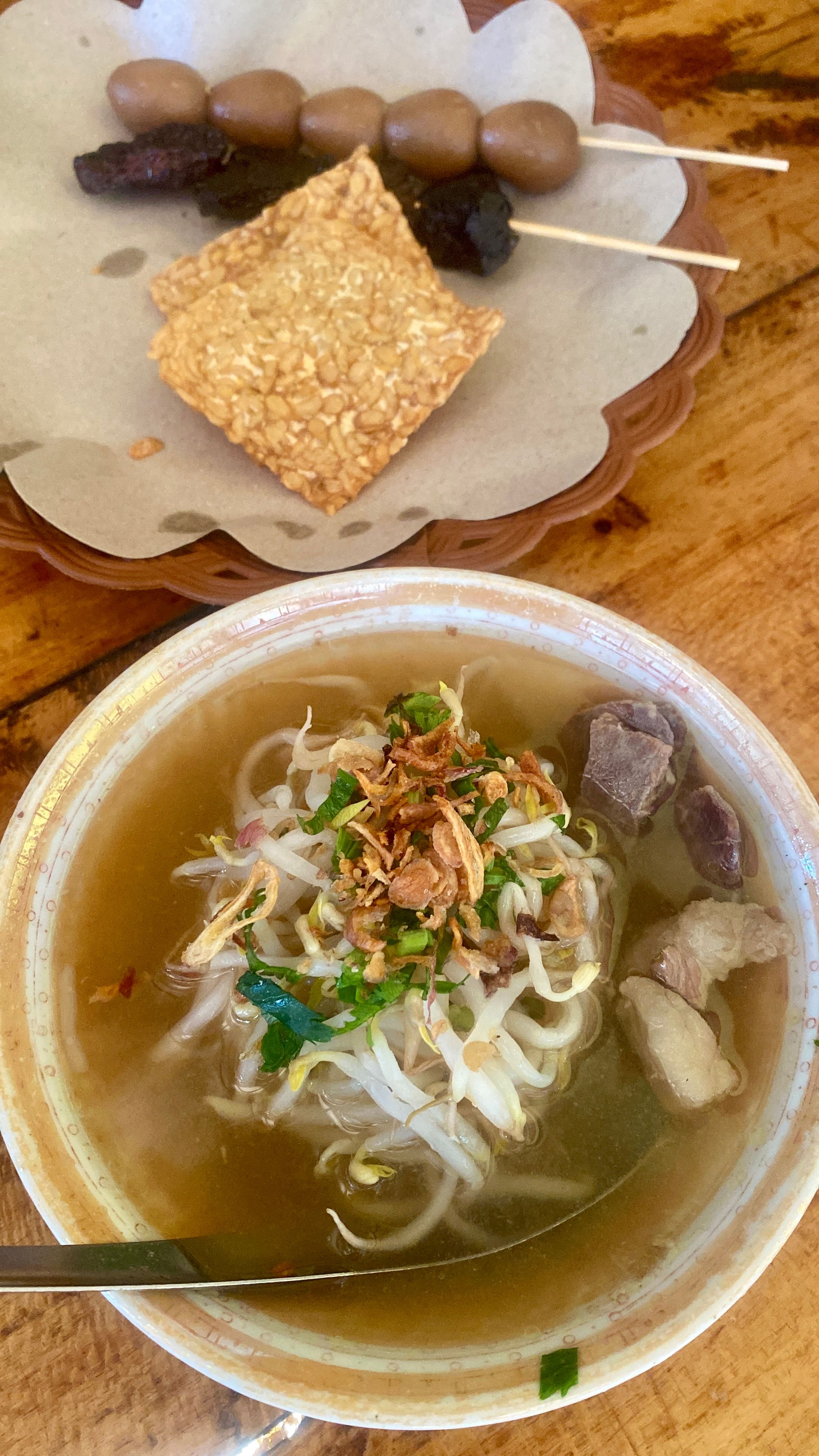 Delicious bowl of Indonesian noodle soup with skewered snacks in Jawa Barat.