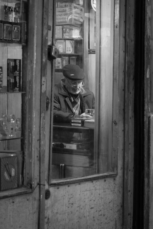 Free Black and white photo of an elderly man reading inside a quaint Istanbul shop, creating a nostalgic mood. Stock Photo