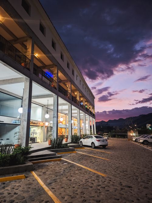 Free A two-story commercial building with parked cars at sunset, showcasing modern architecture. Stock Photo