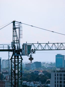 A construction crane operates over a city skyline on a bright day.