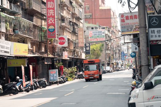 A busy urban street in Taipei, Taiwan, showcasing local businesses and bustling traffic on a sunny day.
