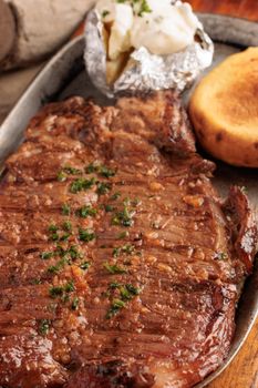 Juicy grilled steak with baked potato and arepa, perfect for a savory Colombian meal.