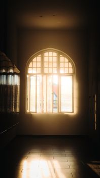 Sunlight streaming through an arched window casting shadows in a Kuala Lumpur hallway.