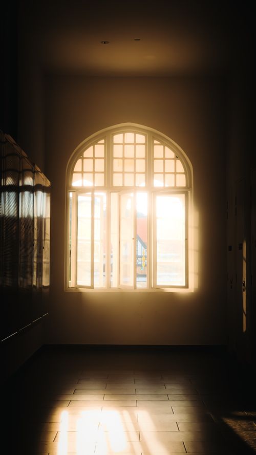 Free Sunlight streaming through an arched window casting shadows in a Kuala Lumpur hallway. Stock Photo
