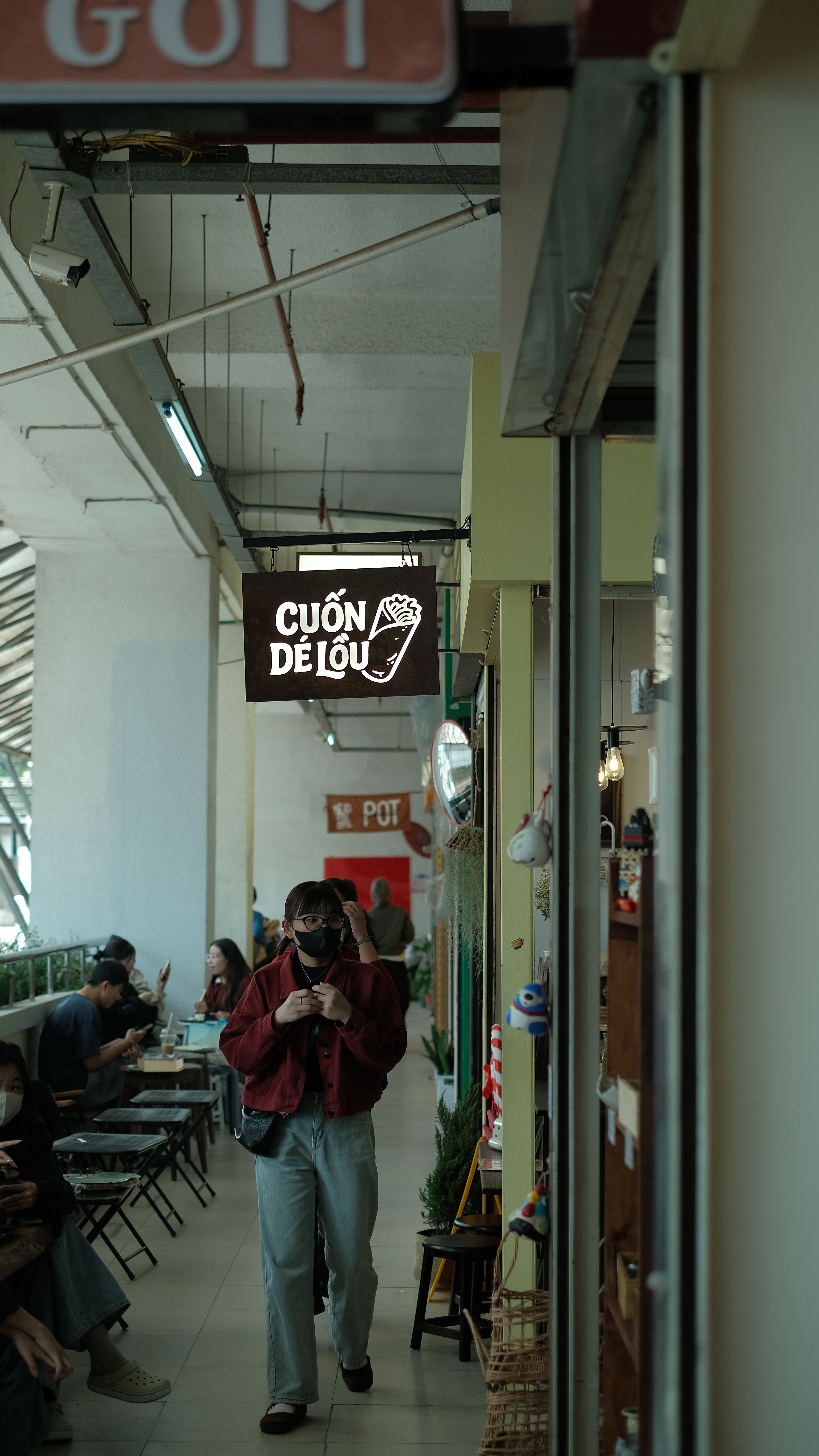 A bustling indoor market with people dining and walking, featuring local signage.