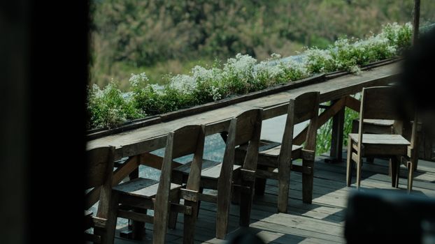 Charming outdoor seating with wooden chairs and blooming flowers on a sunny day.