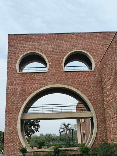 Free Brick building in India with distinct circular windows resembling a face, creating a playful architectural design. Stock Photo