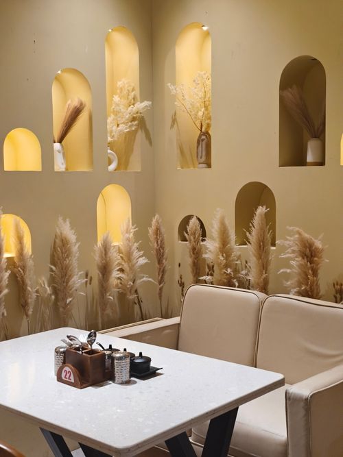 Free Elegant cafe setting with a minimalist design, featuring decorative niches and pampas grass arrangement. Stock Photo