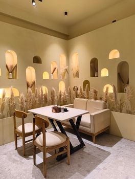 Warm cafe interior with stylish table and chairs, decorative shelves and muted lighting.