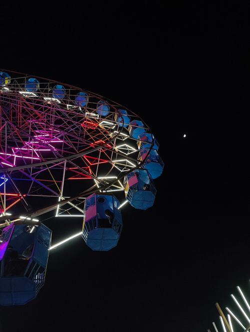 Free A vibrant Ferris wheel lit up with colorful lights against the dark night sky in India. Stock Photo