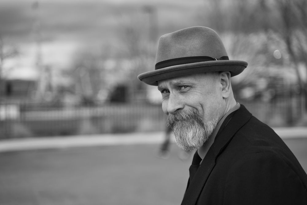 An older man in a hat smiling in black and white