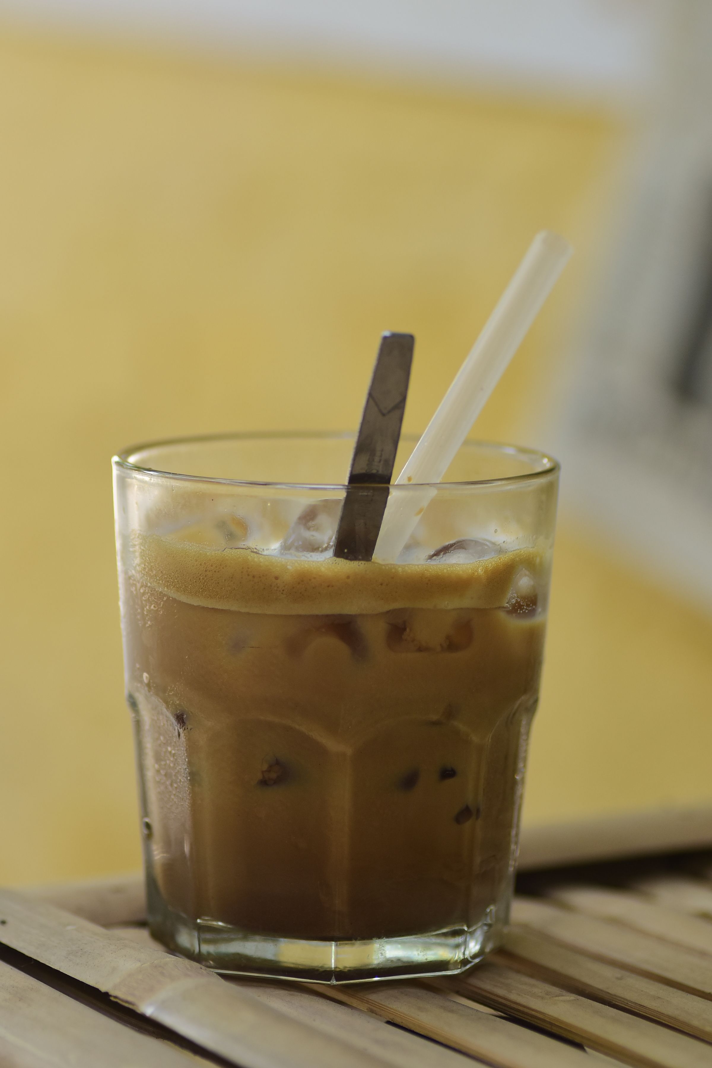 Cold iced coffee in a glass with straw and ice cubes, perfect for a summer refreshment.