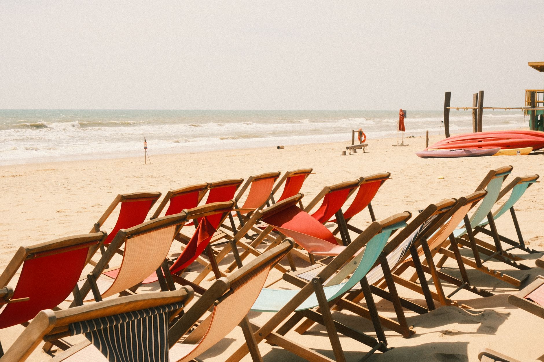 Rows of colorful beach chairs on a sandy shore in Phan Thiet, Vietnam, under bright sun.