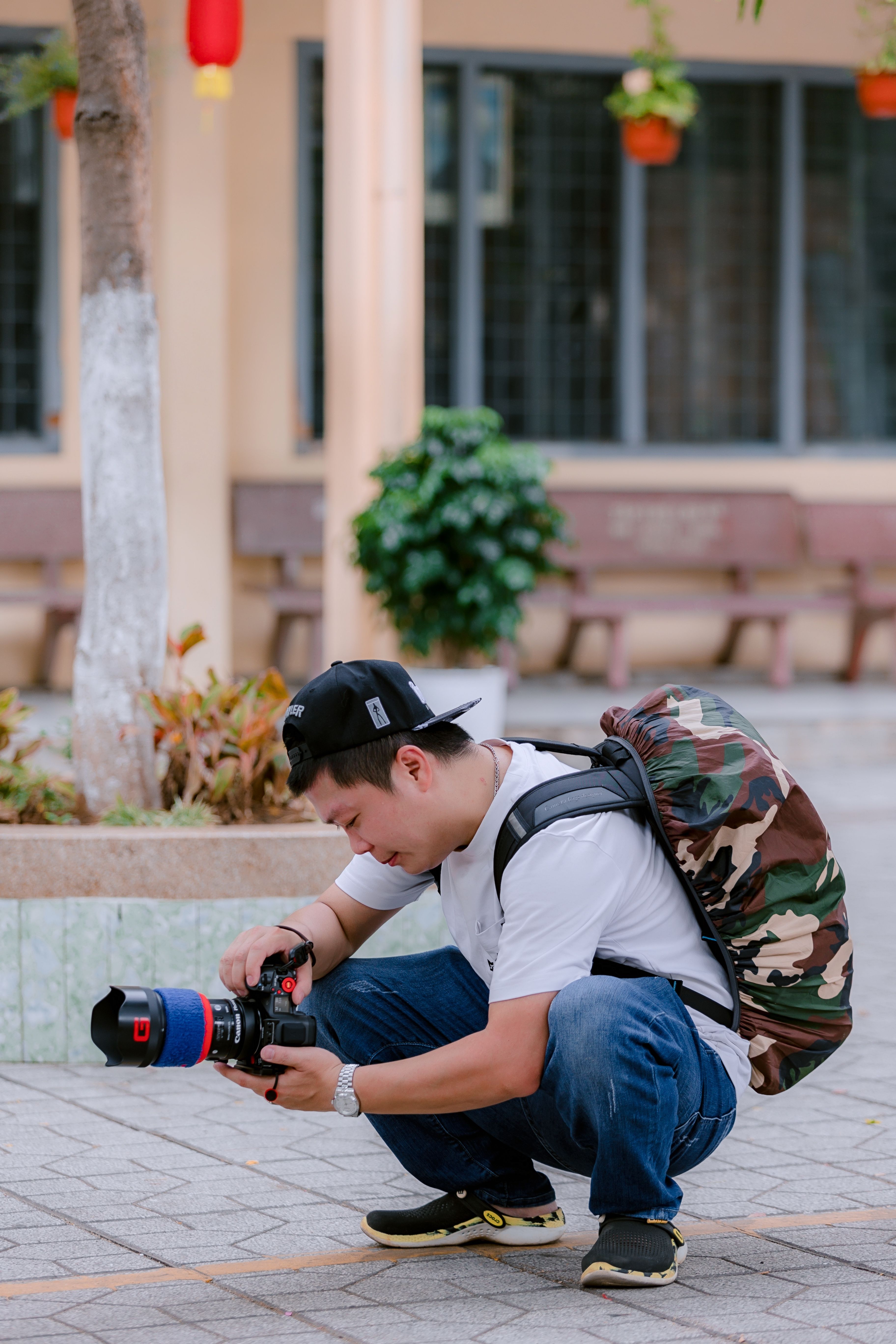 Photographer crouching with camera outdoors capturing image details.
