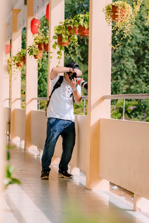 Free A male photographer with a large lens camera shooting on a sunny corridor. Stock Photo