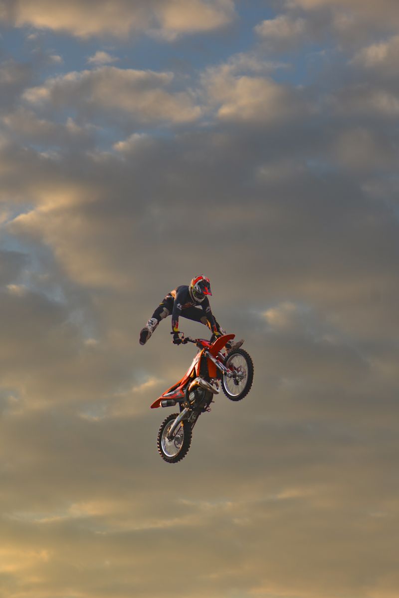 Motocross rider mid-stunt against a dramatic cloudy sky — photo by Pavel Khlystunov on Pexels