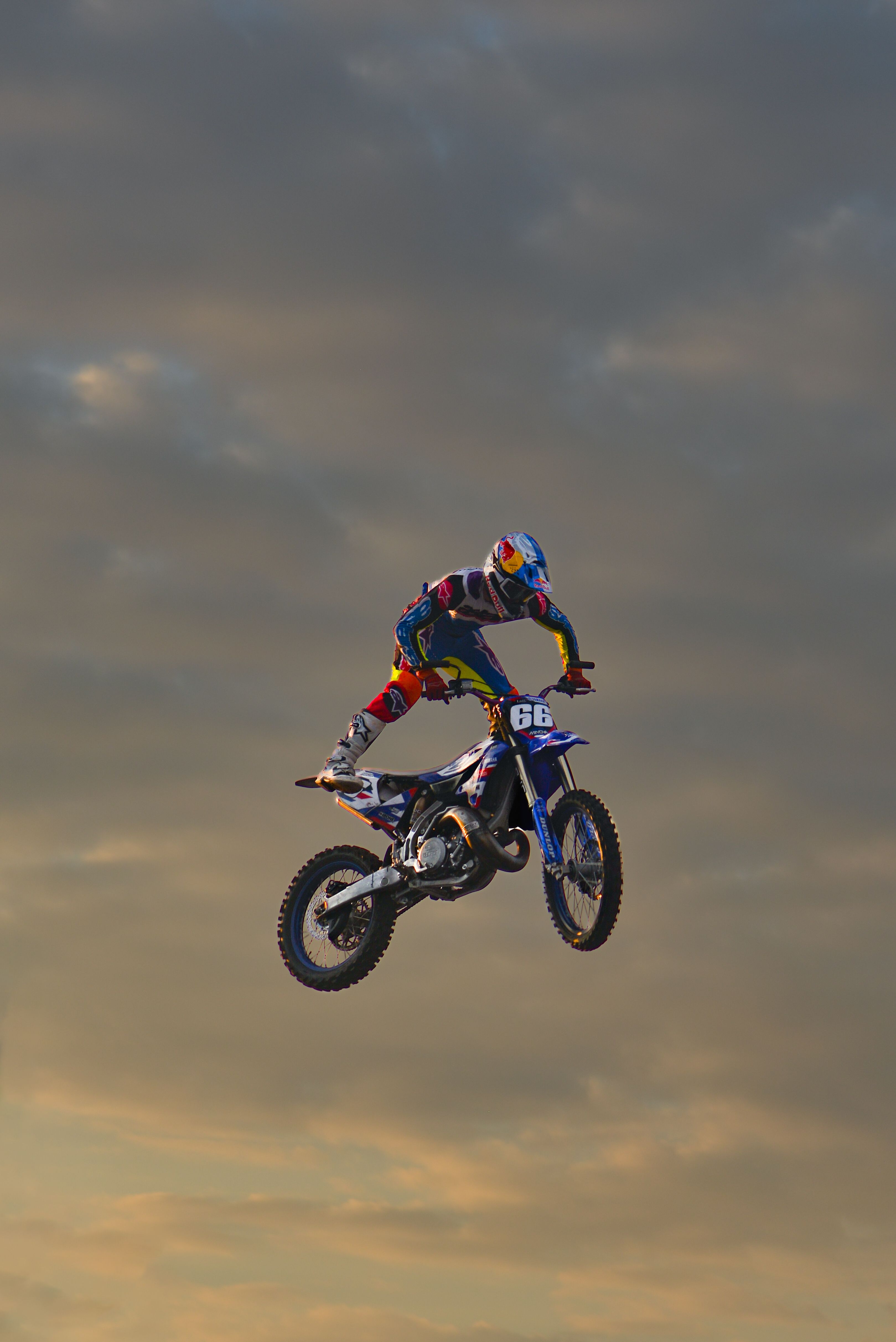 High-flying motocross rider performing a stunt against a dramatic sky.