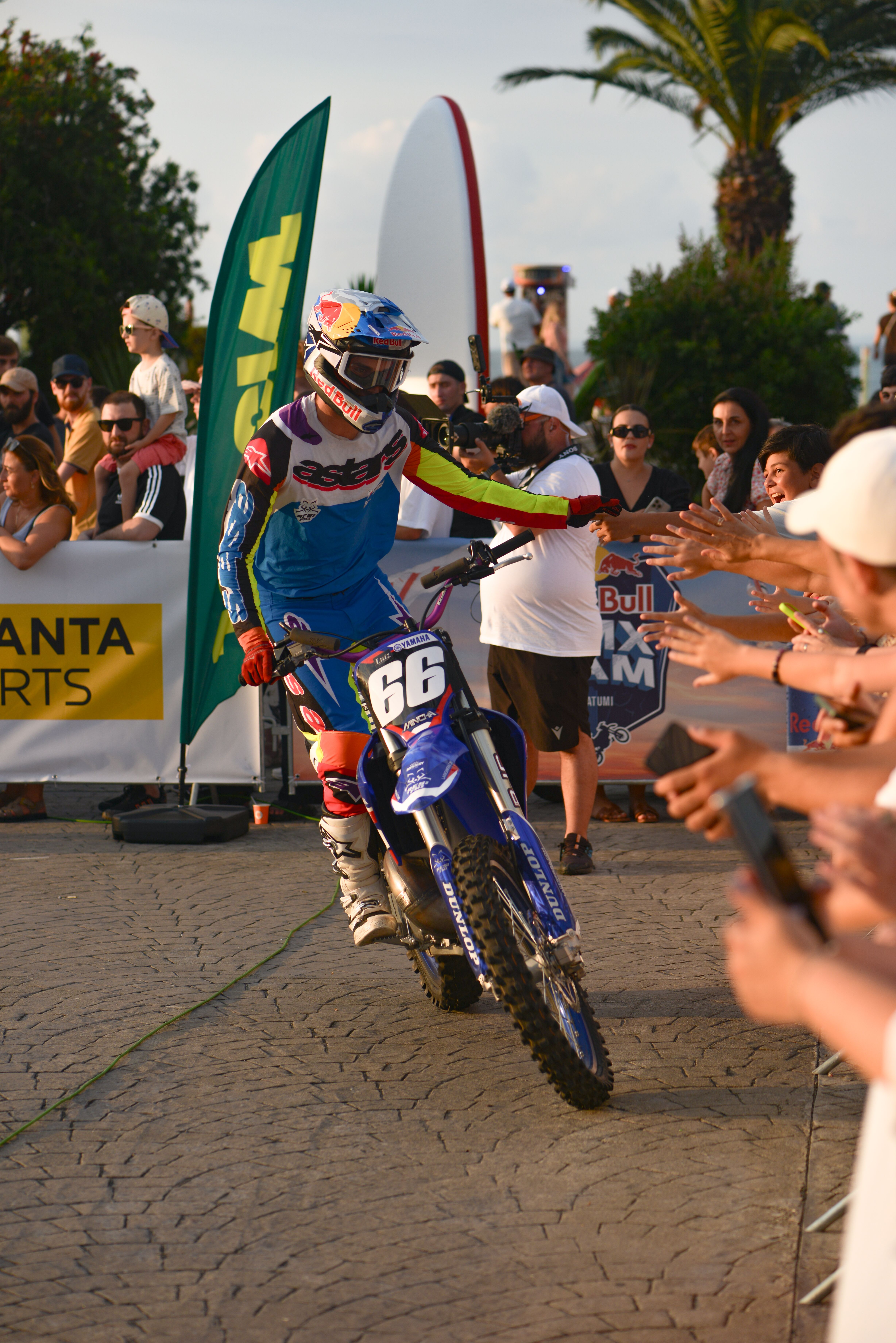 Motocross rider high-fives fans during an exciting outdoor sporting event.