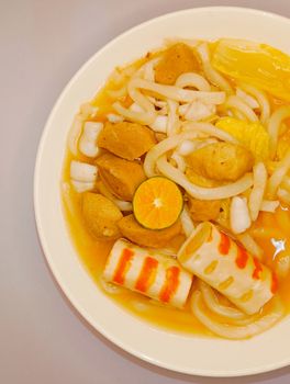 Warm and inviting Asian noodle soup with fish balls and citrus garnish, perfect for cozy meals. - Fotografer Sidoarjo